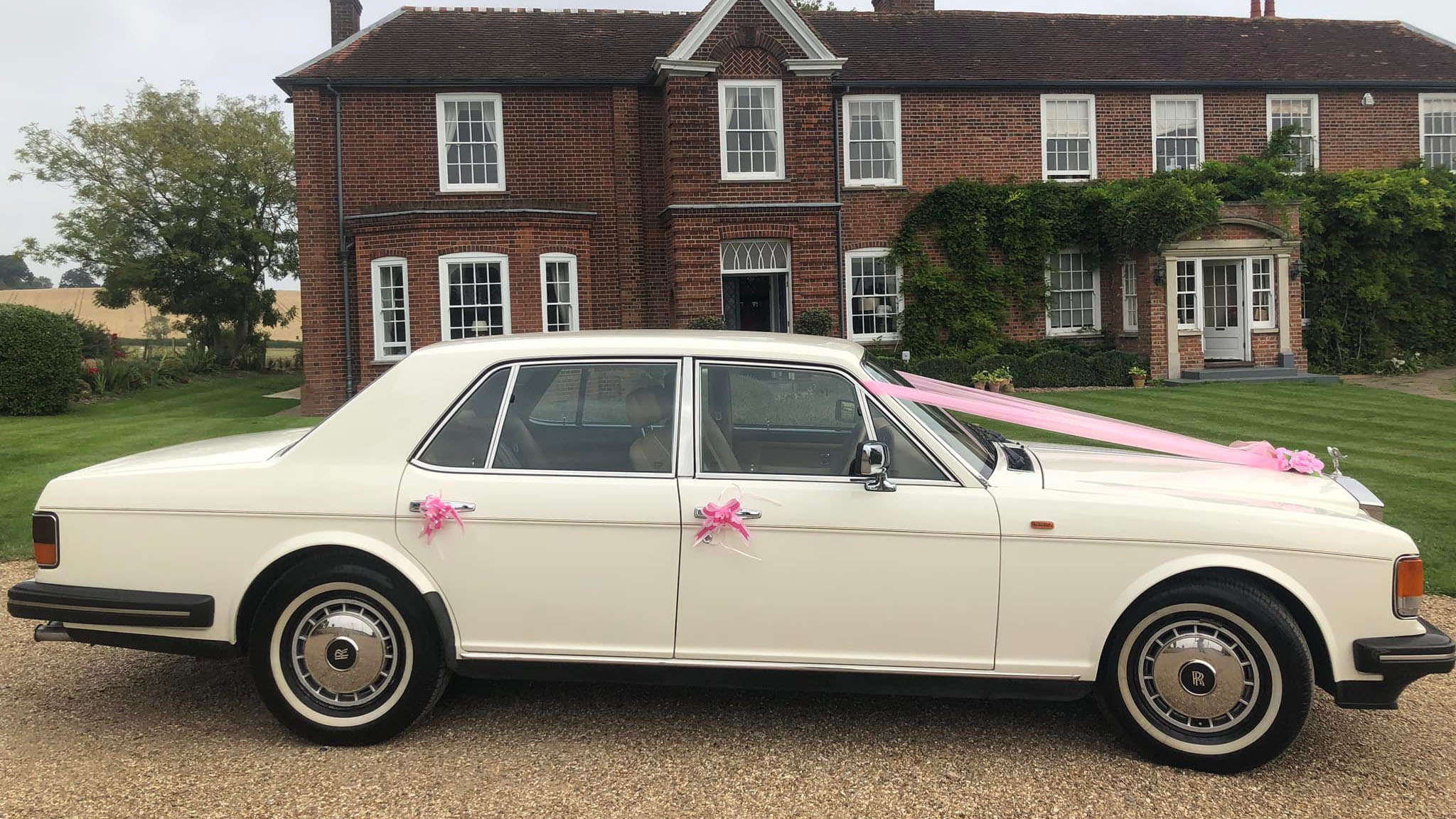 Rightside view of a classic Rolls-Royce Silver Spirit with pink ribbons and bows on door handles