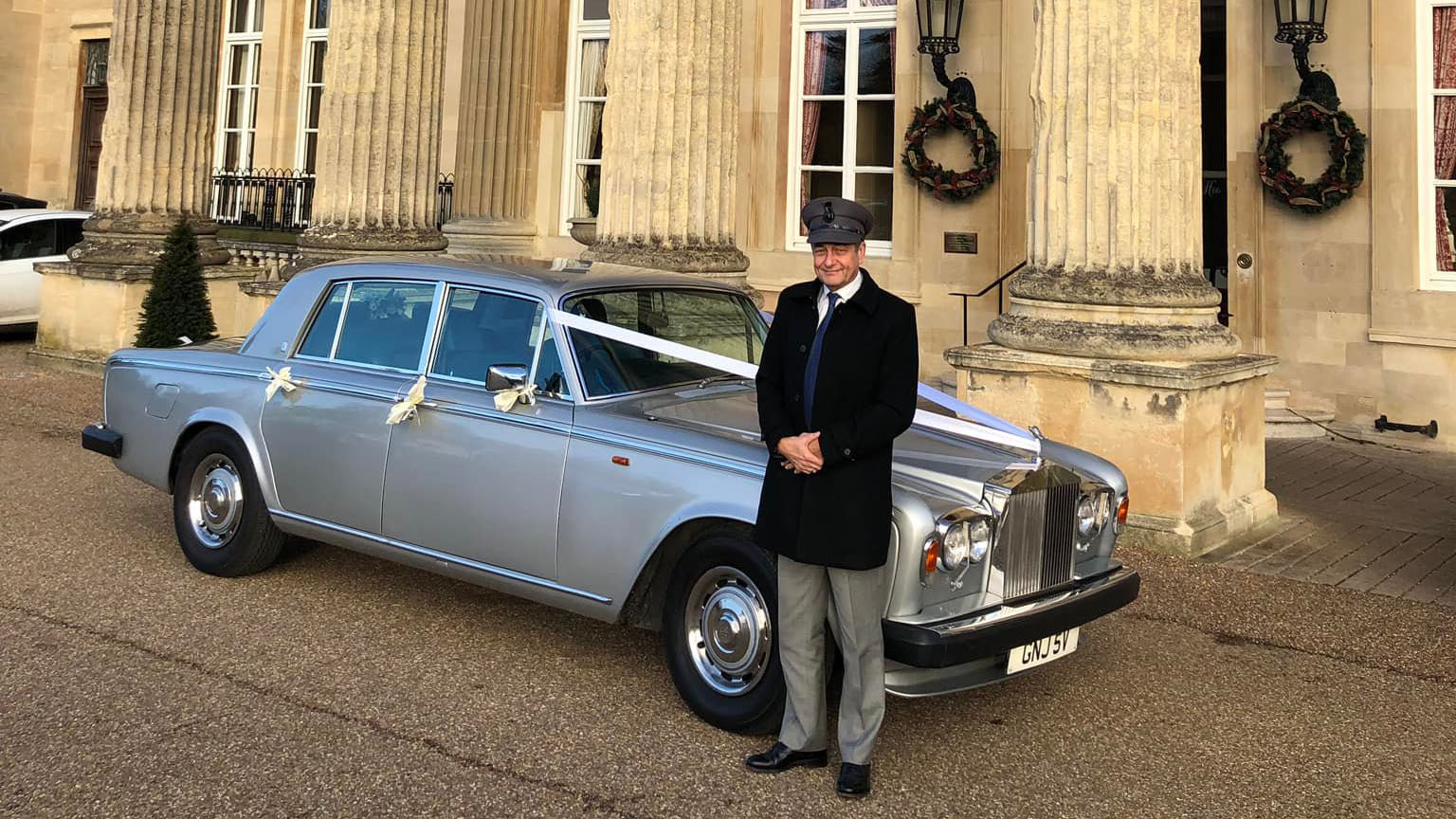 chauffeur wearing his winter coat in standing on front of a classic Rolls-Royce Silver Shadow