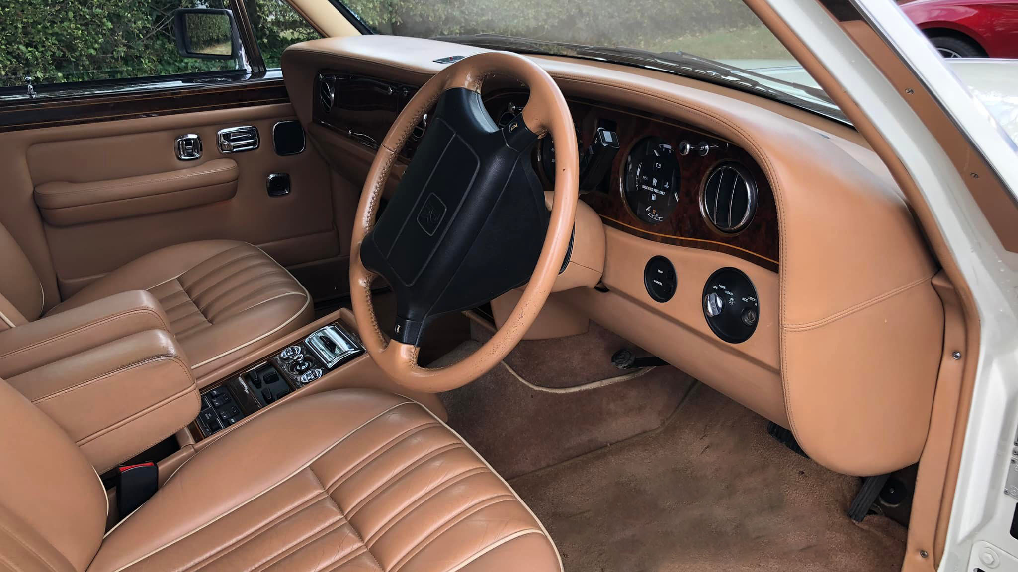 tan leather interior front seating with cream carpet and wooden dashboard