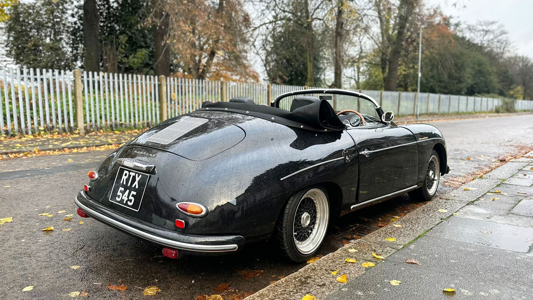 Rear view of Black Porsche with black soft-top roof open