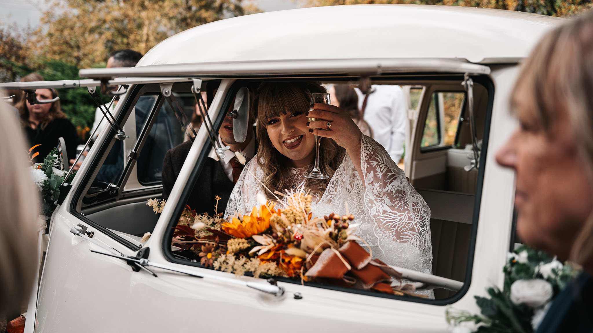 Bride cheering with a glass of Champagne inside a vw campervan