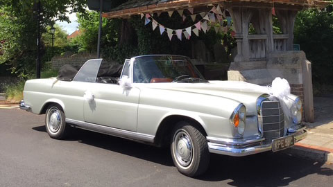 Right side view of a classic Mercedes Convertible with white ribbons