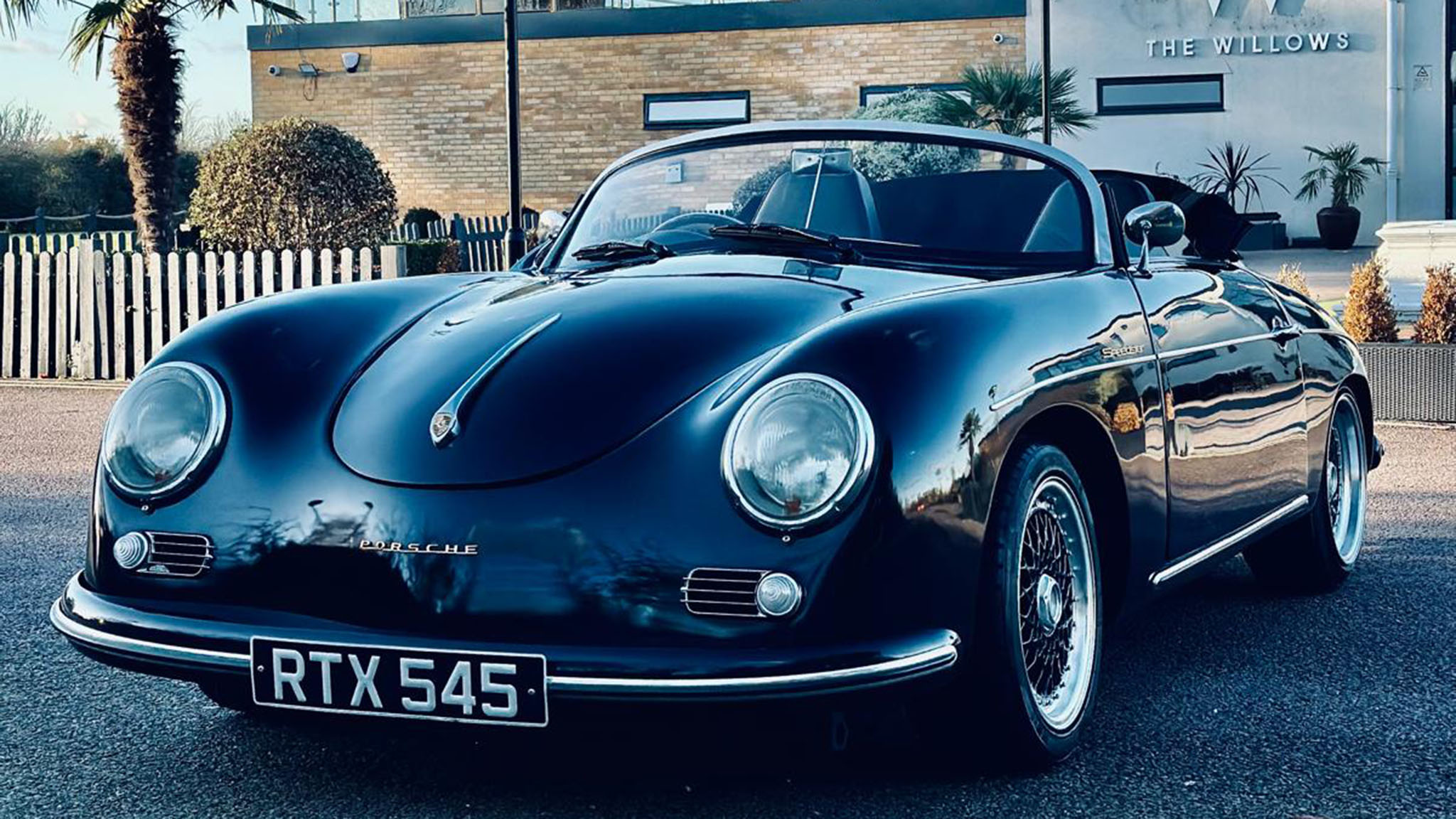 Front left view of black convertible Porsche with soft top roof down