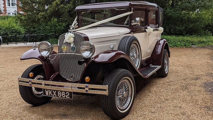 vintage Badsworth wedding car in Ivory with Burgundy wheel arches and roof decorated with white wedding ribbons