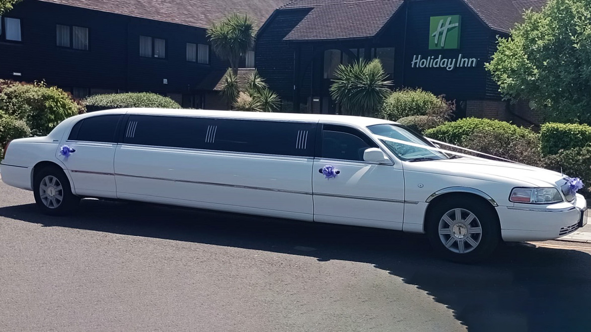 Right side view of a white stretched limousine parked in front of Holiday Inn in Southampton