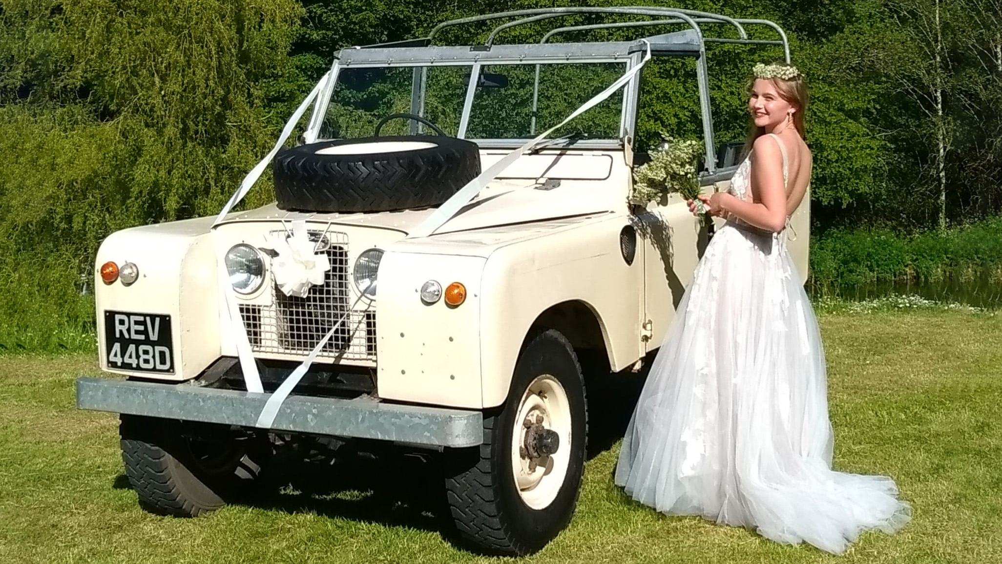 Bride wearing a white dress standing next to a Classic Land Rover