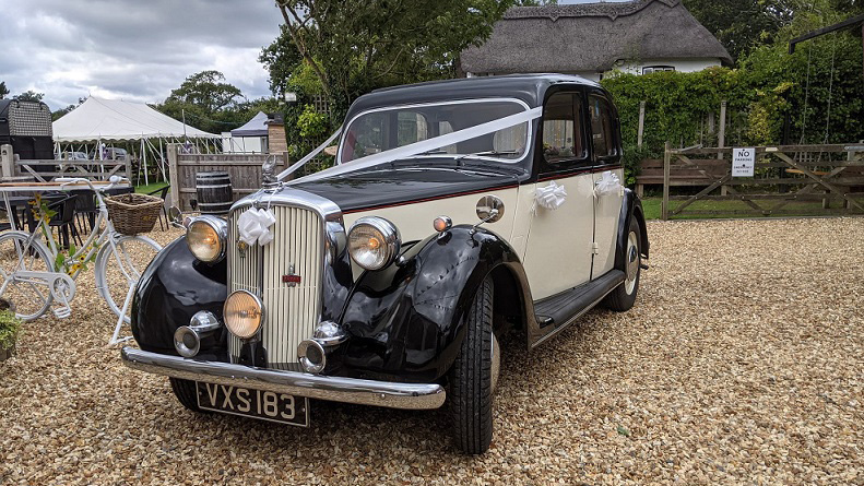 Black and ivory vintage Rover p3 decorated with wedding ribbons at a wedidng venue