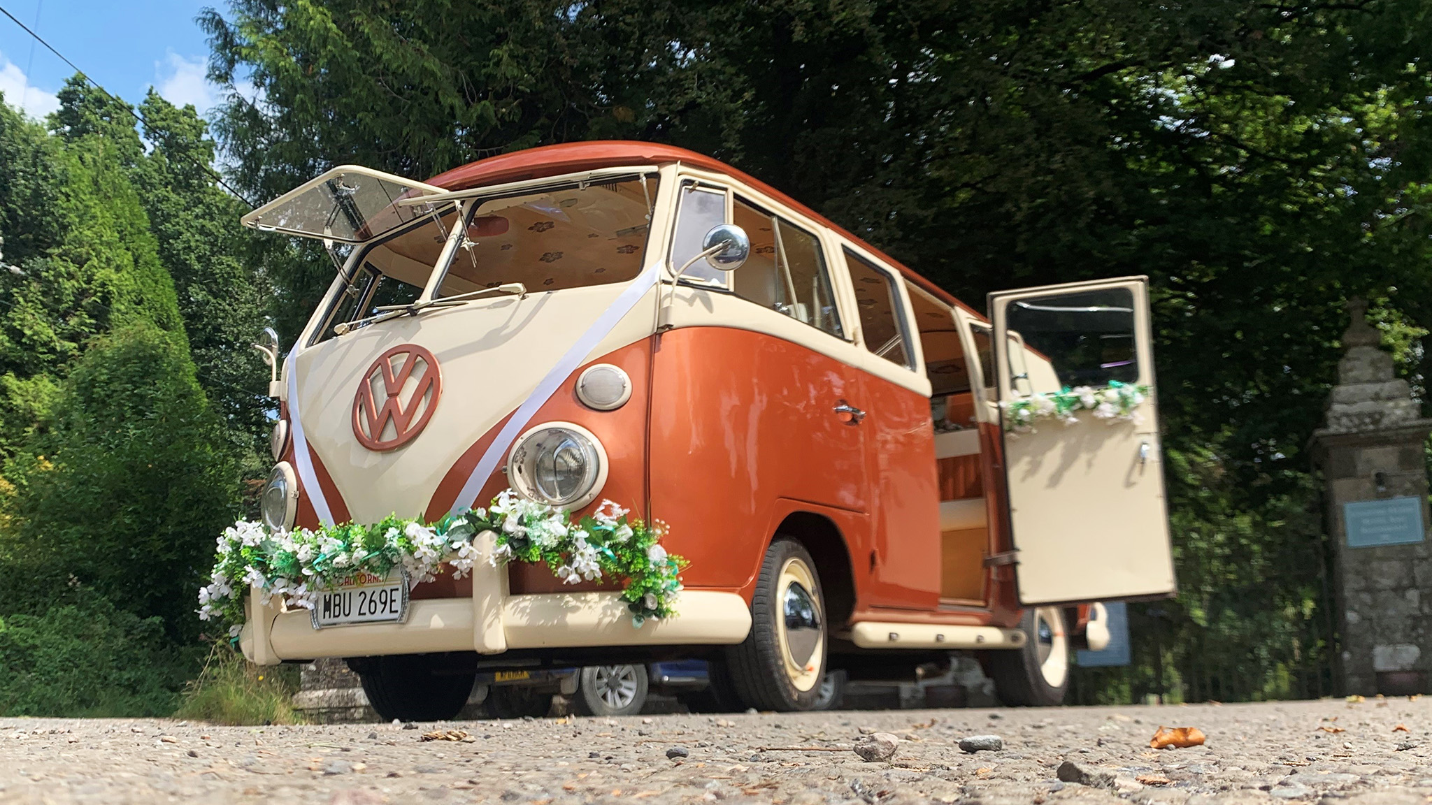 Classic splitscreen campervan with rear passenger door open and front windows open in White and Burnt Orange