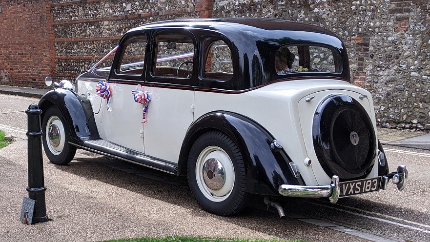 rear view of a black and ivory vintage Rover p3 decorated with purple ribbons