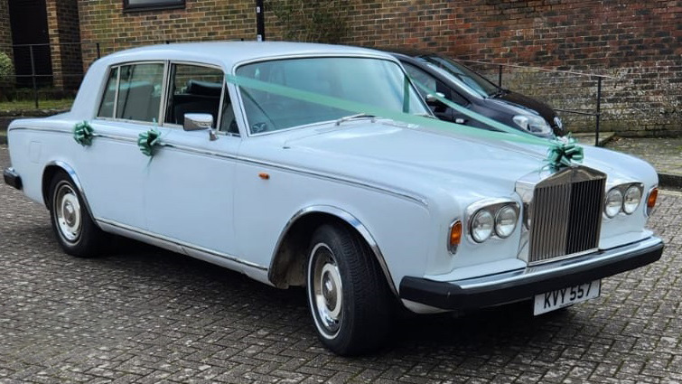 Classic white wedding car with ribbons and bows on door handle