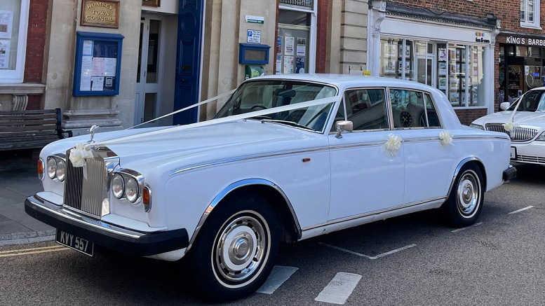 Left side view of classic Rolls-Royce decorated with white ribbons in the street of Southampton