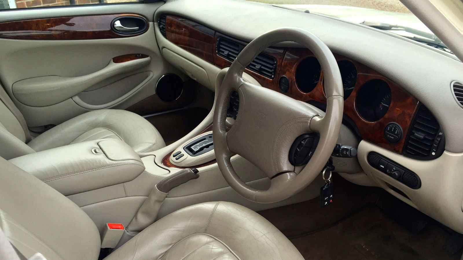 Wooden dashboard and cream leather seats interior front view of a Jaguar car