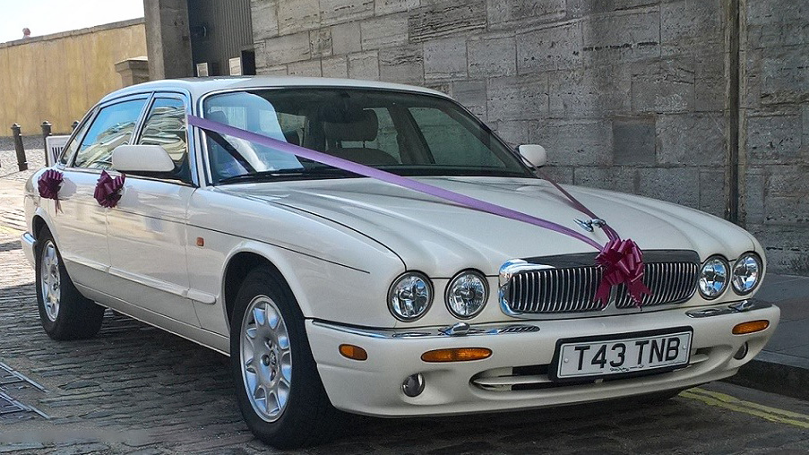 White Jaguar parked in southampton with Purple ribbons and red bows