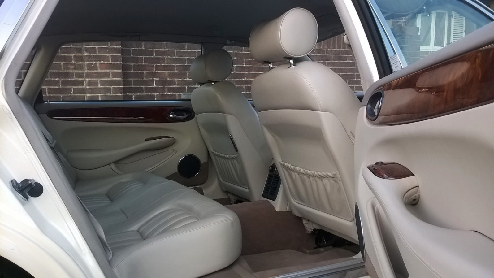 Rear seating in Jaguar with cream leather interior and wooden features on top of the door cards