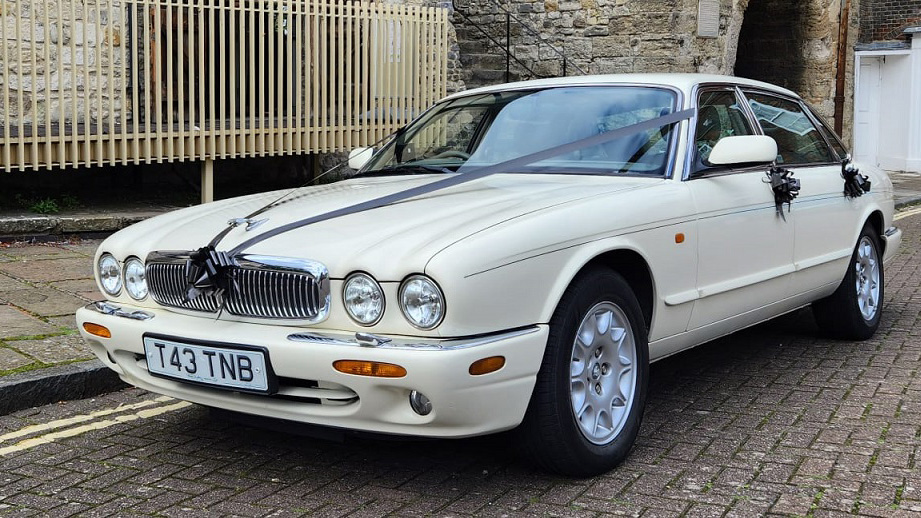 Modern white Jaguar with Royal  blue wedding ribbons and bows on door handles