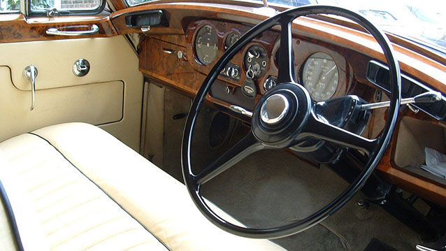 Front interior area inside a Bentley S1 with cream leather seat and wooden dashboard