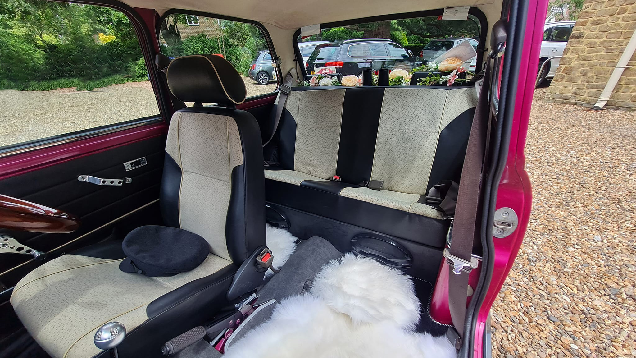 Black and Cream two-tone interior seats inside Classic Austin Mini. Chauffeur's hat on front driver's seat