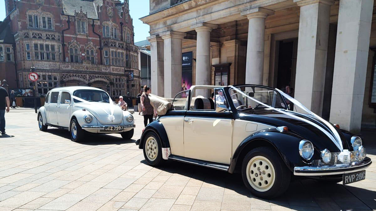 Black & Ivory Beertle with convertible roof followed by a white Stretched Beetle both dressed with matching wedding ribbons