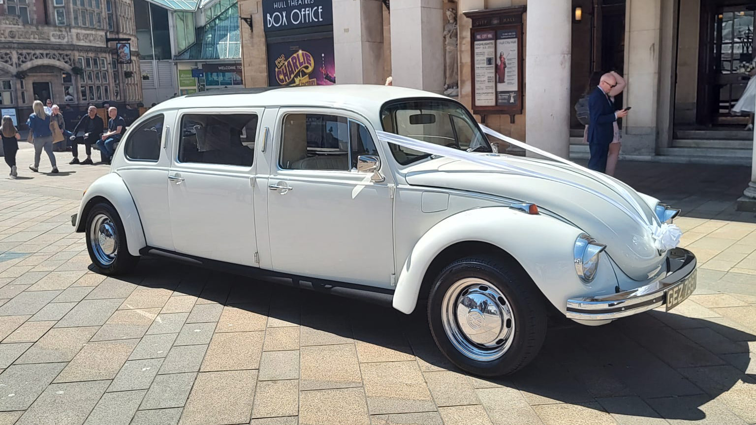 Classic Beetle in Ivory dressed with white ribbons parked in front of Registrar's office