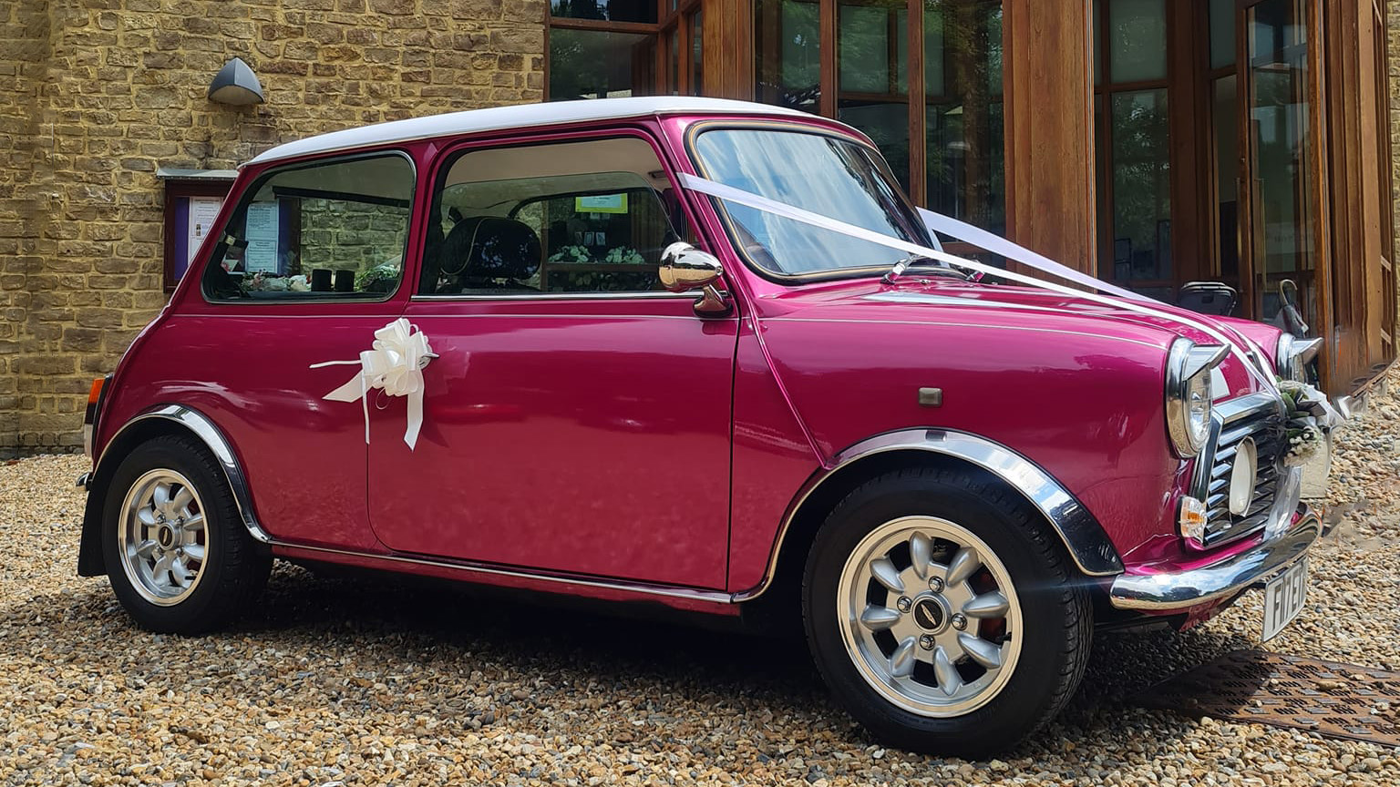 Right side view of classic Austin Mini in Pink with with ribbons and bows