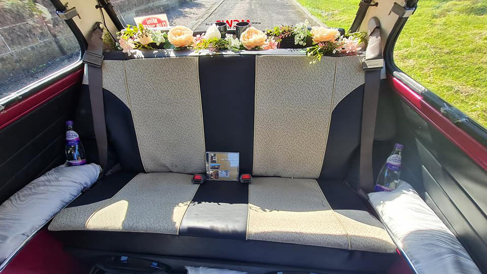 Interior rear seats inside Austin Mini with two-tone black and Ivory seats and flowers on the parcel shelf.