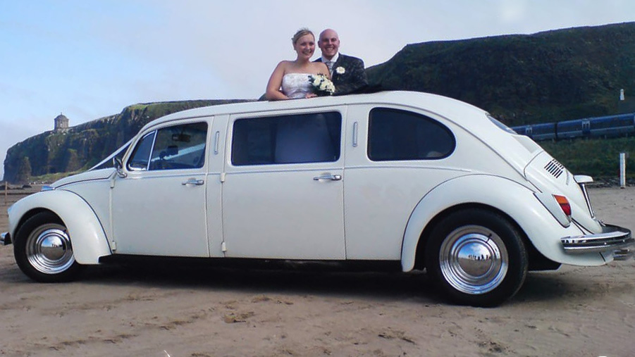 Bride and Groom standiong inside a classic VW stretched limousine with their head through the sunroof