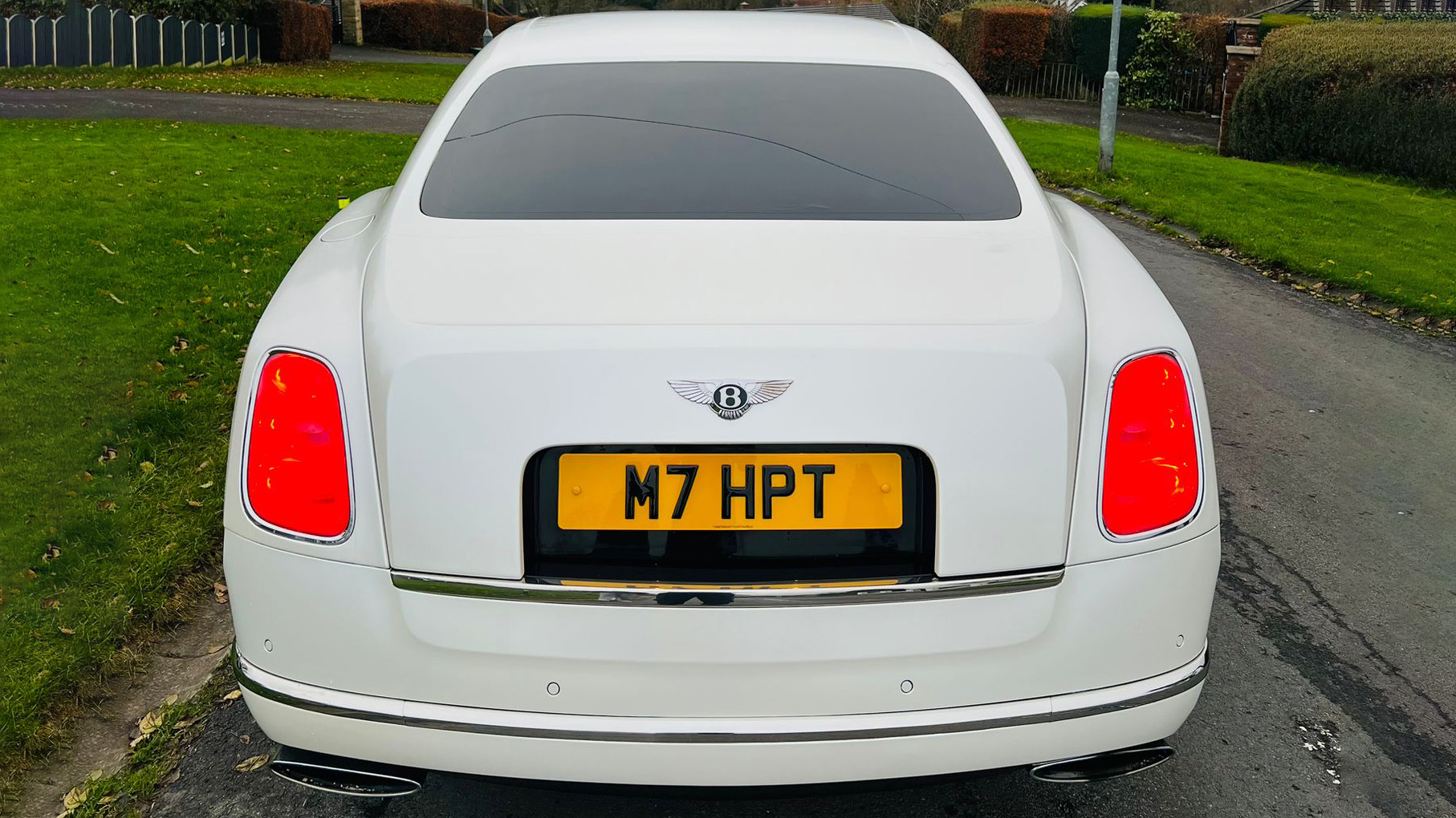 Full rear view of White Bentley Mulsanne with rear lights on