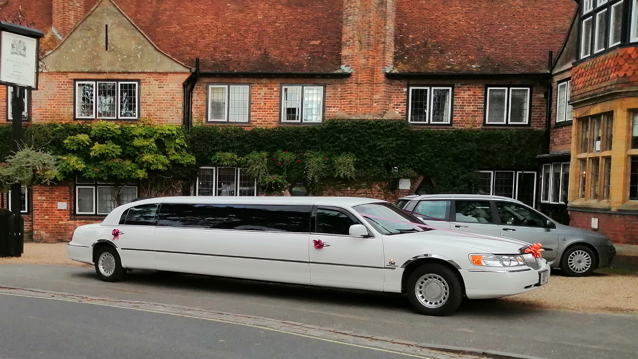 Right side view of a white stretched limousine decorated with wedding ribbons