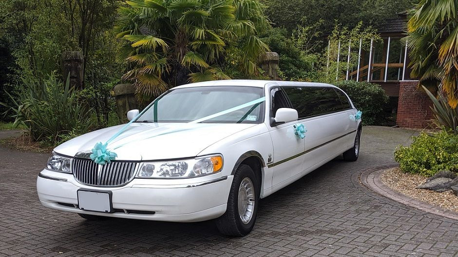 Modern White stretched limousine decorated with light blue ribbons and bow