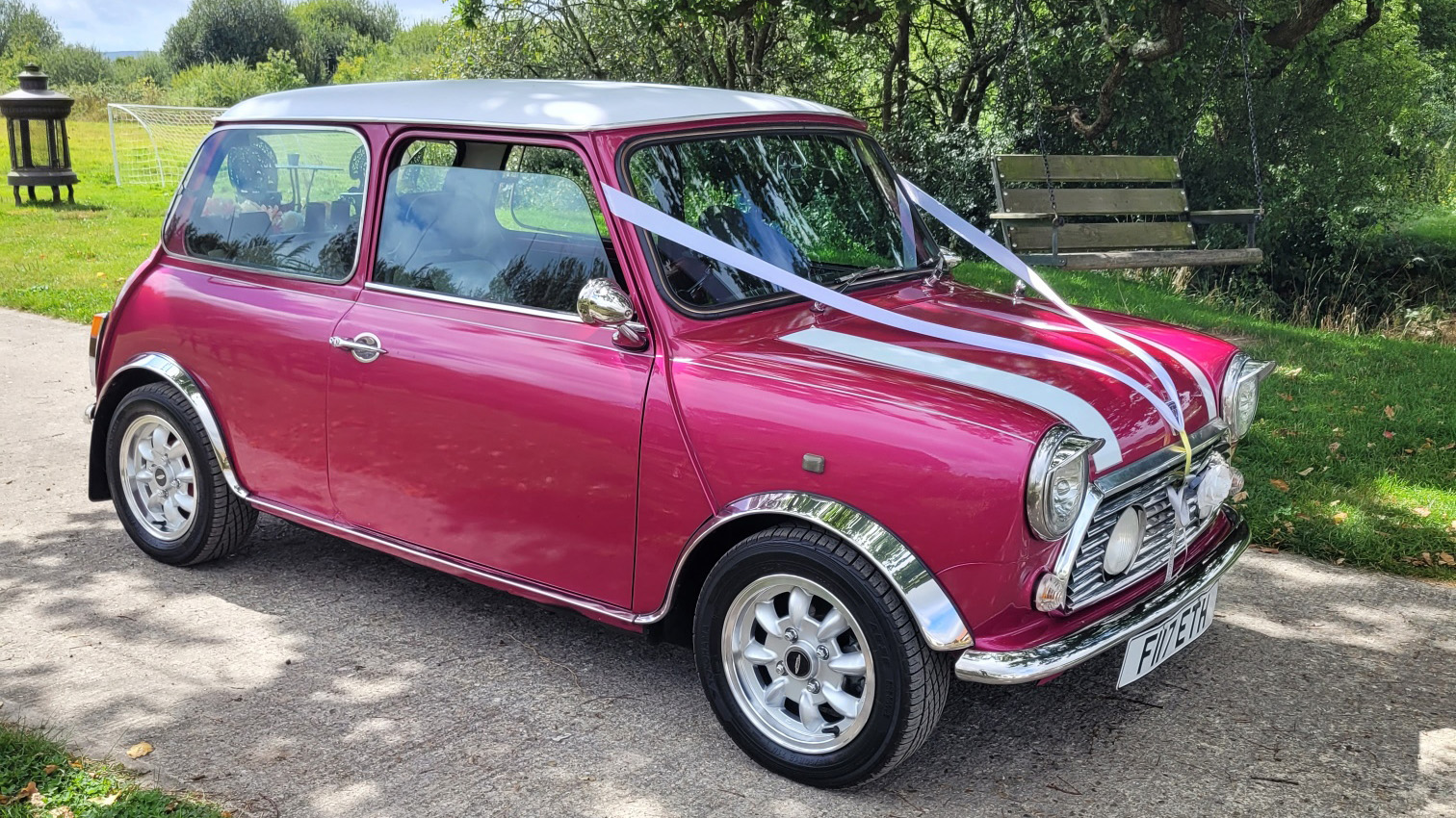 Pink austin Mini decorated with wedding ribbons