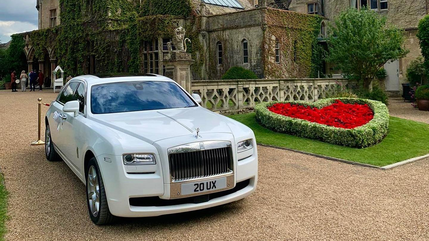 White Rolls-Royce Ghost at wedding venue with heart-shape flower bed in the background