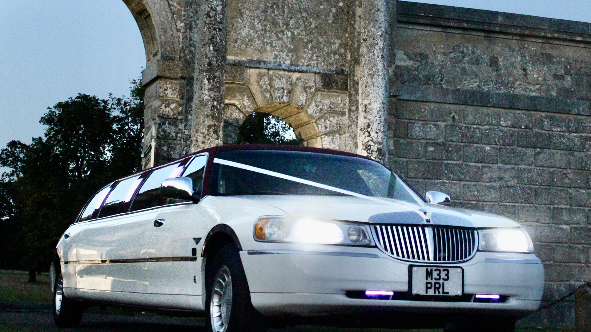 White Wedding Limousine with white  ribbons and headlights on