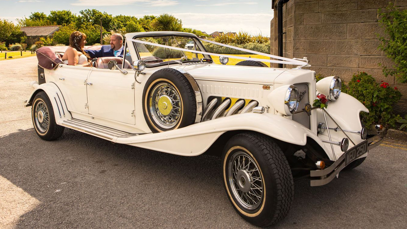 Bride and Groom seating inside a vintage Beauford with convertible roof down