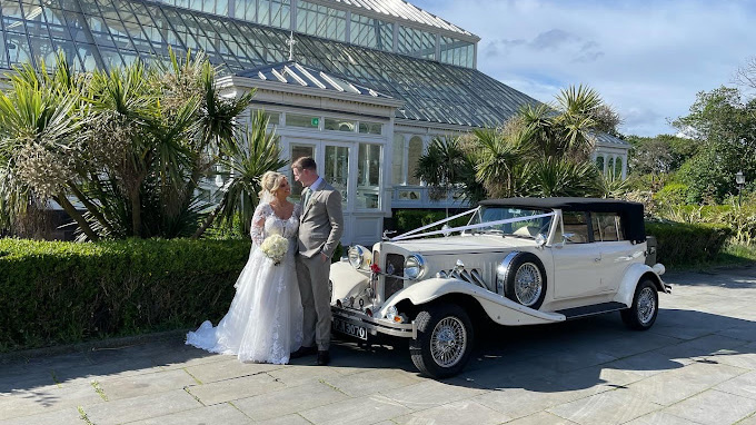 Vintage Beauford decorated with wedding ribbons parked in front of a wedding venue in Liverpool with Bride and Groom standing by the vehicle