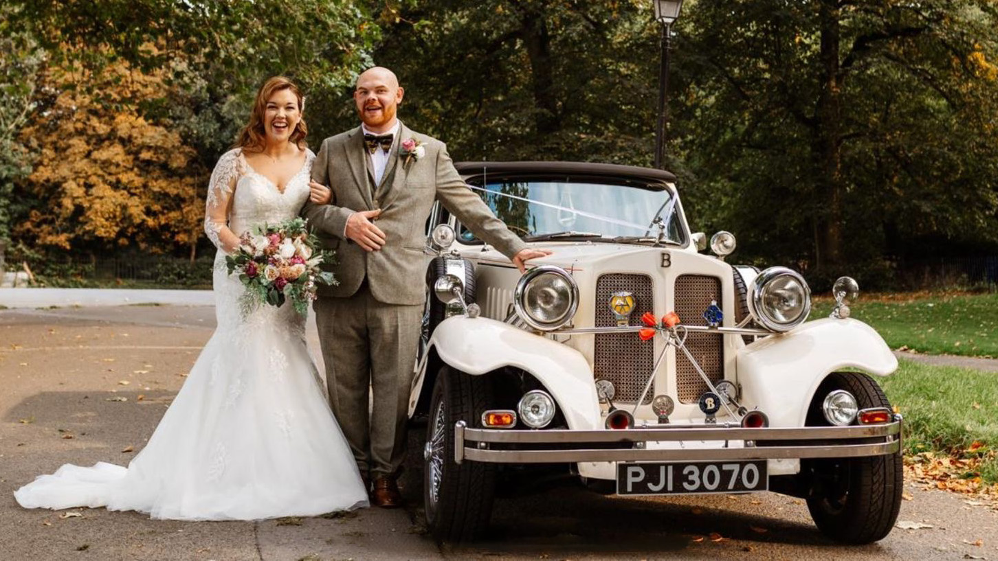 Bride and Groom standing by a vintage Beauford