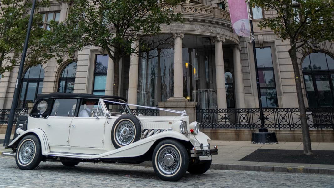 Right side view of a vintage style BEauford with black soft top roof closed and spare wheel mounted on the side of the vehicle