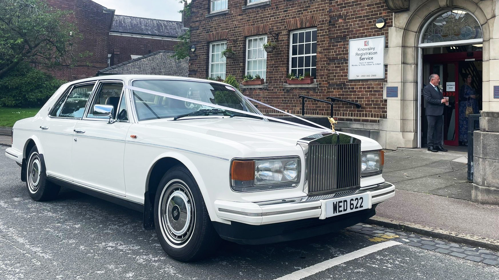 White classic Rolls-Royce with white wedding ribbons parked in front of venue in Liverpool