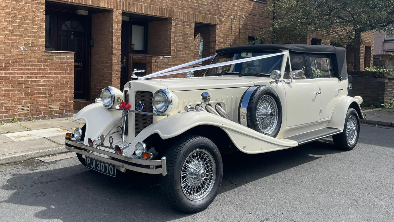 Vintage Beauford in Old English White with Black soft top roof and descorated with white wedding ribbons