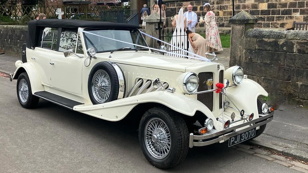 Vintage Beauford with black soft top roof parked in front of a church in liverpool