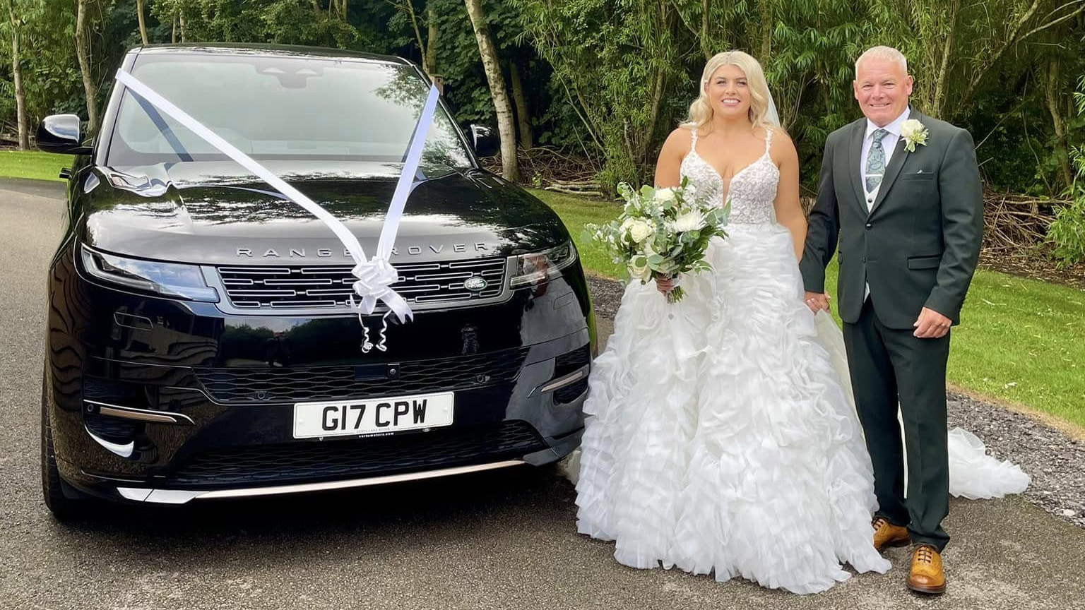 Bride and Groom holding hands and standing on the left side of a Black Range Rover