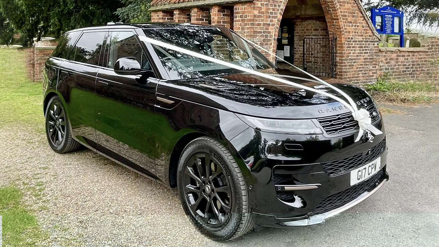 Black Modern Range Rover decorated with white ribbons parked in front of a church in Yrokshire