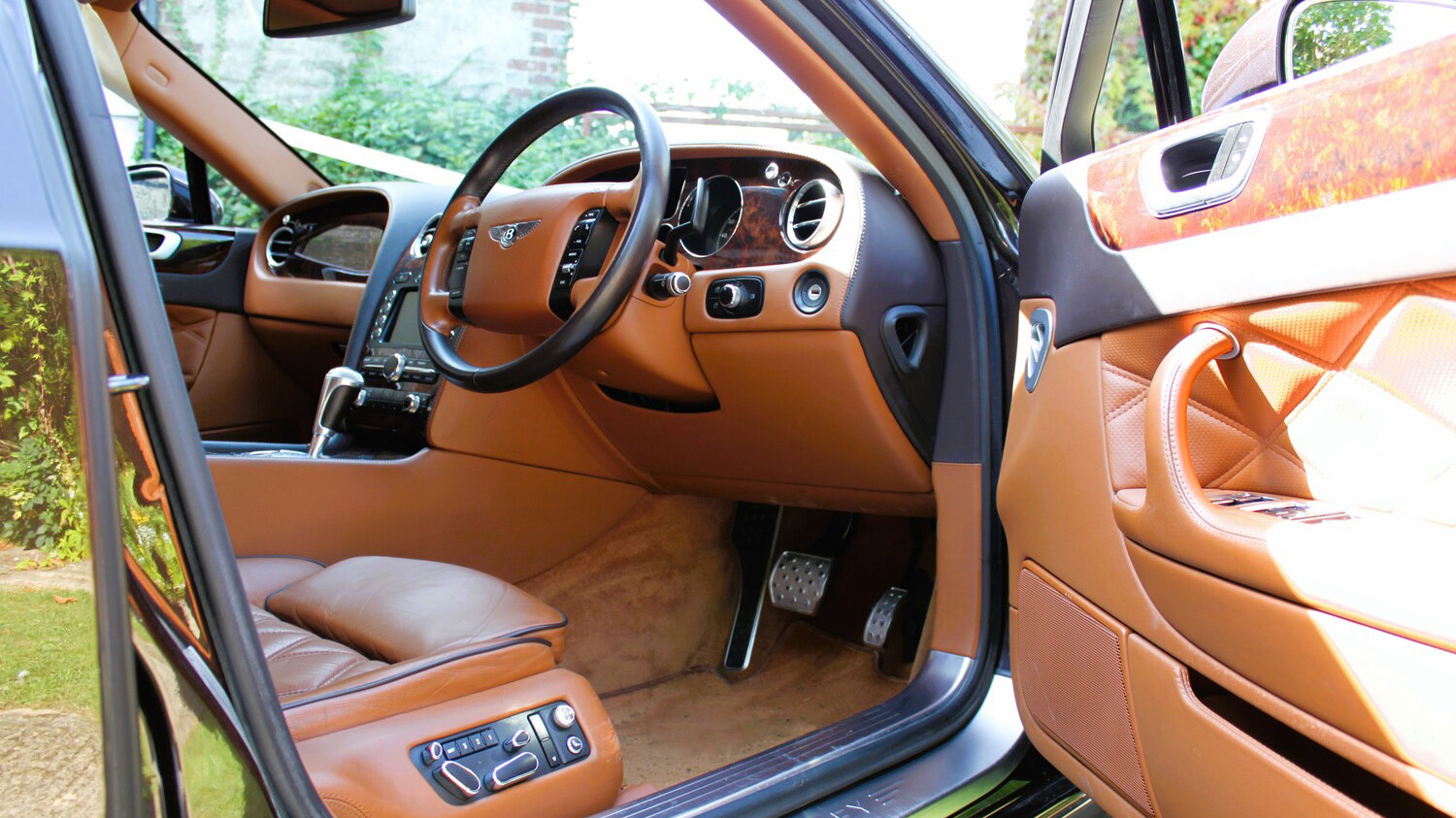 Front driver seat inside a Modern Bentley Flying Spur with Tan Leather interior