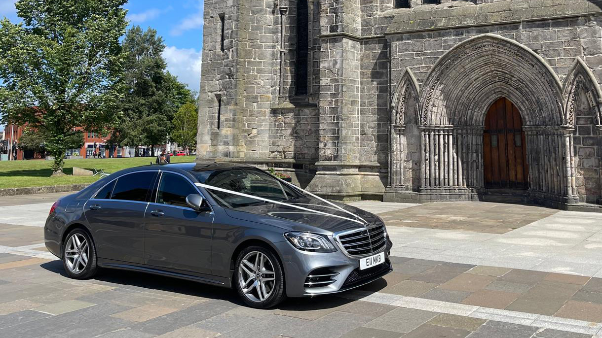 Modern Mercedes decorated with White ribbons parked in front of a cathedral