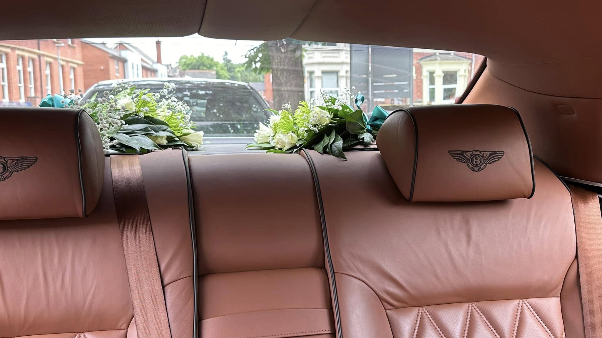 Rear tan leather interior seat head rest with Bentley logo embroidered and floral decoration on the rear parcel shelf