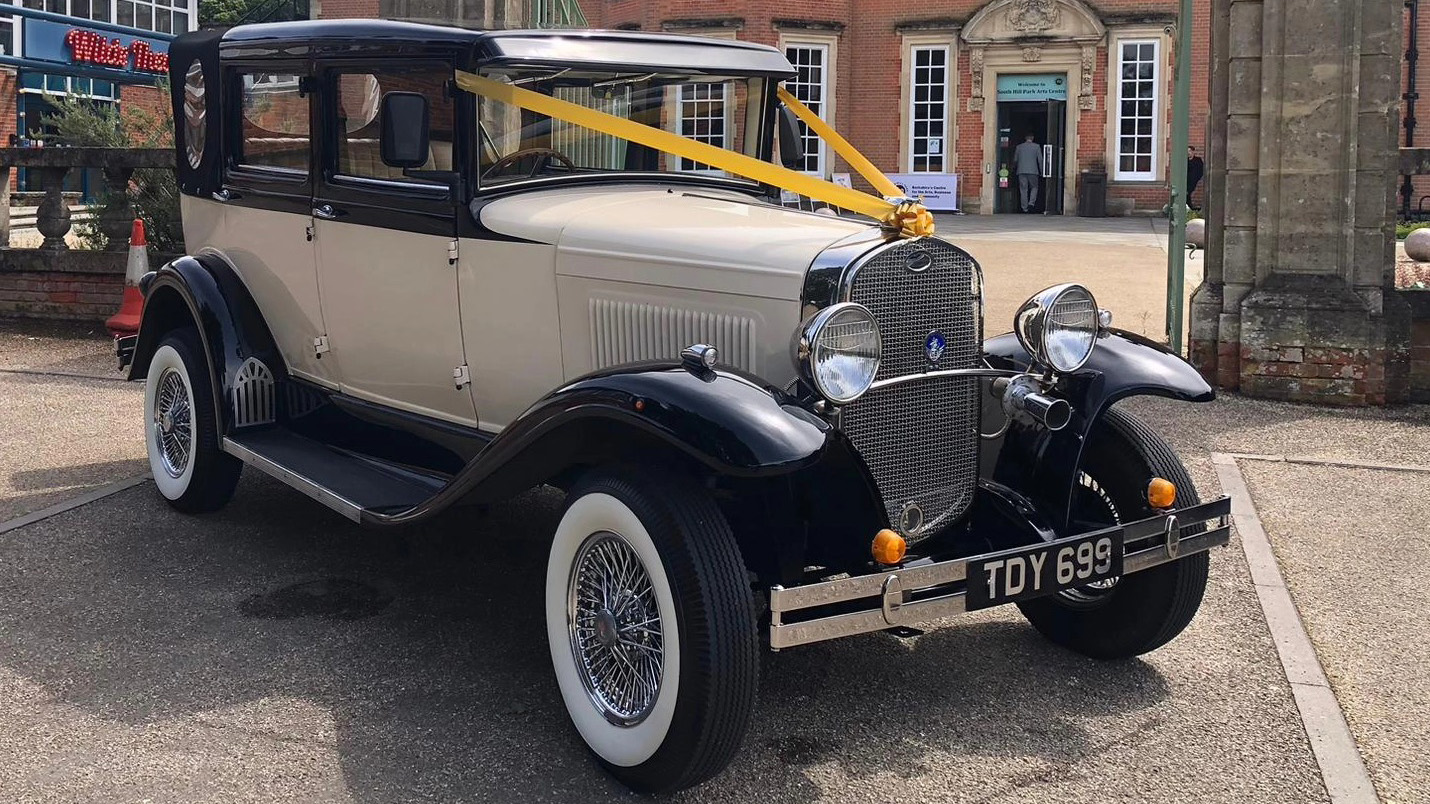 Front right view of Badsworth Landaulette in Ivory with black weehl arches and roof dressed with yellow wedding ribbons