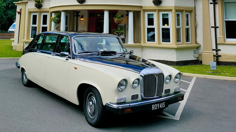 Ivory classic Daimler Limousine with black bonnet and roof in front of a wedding venue in Liverpool