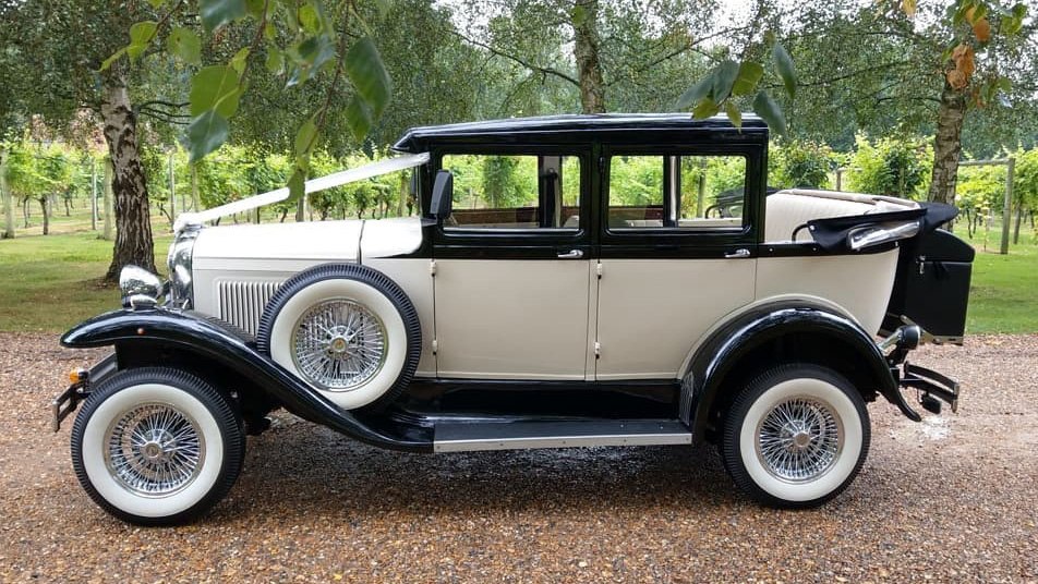 Left side view of a Badsworth Landaulette in Ivory with black wheel arches decorated with ribbons and convertible roof open