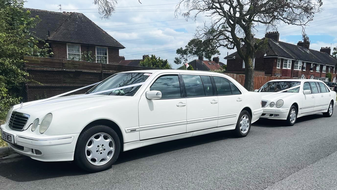 white 6-door Stretched Mercedes decorated with white wedding ribbons