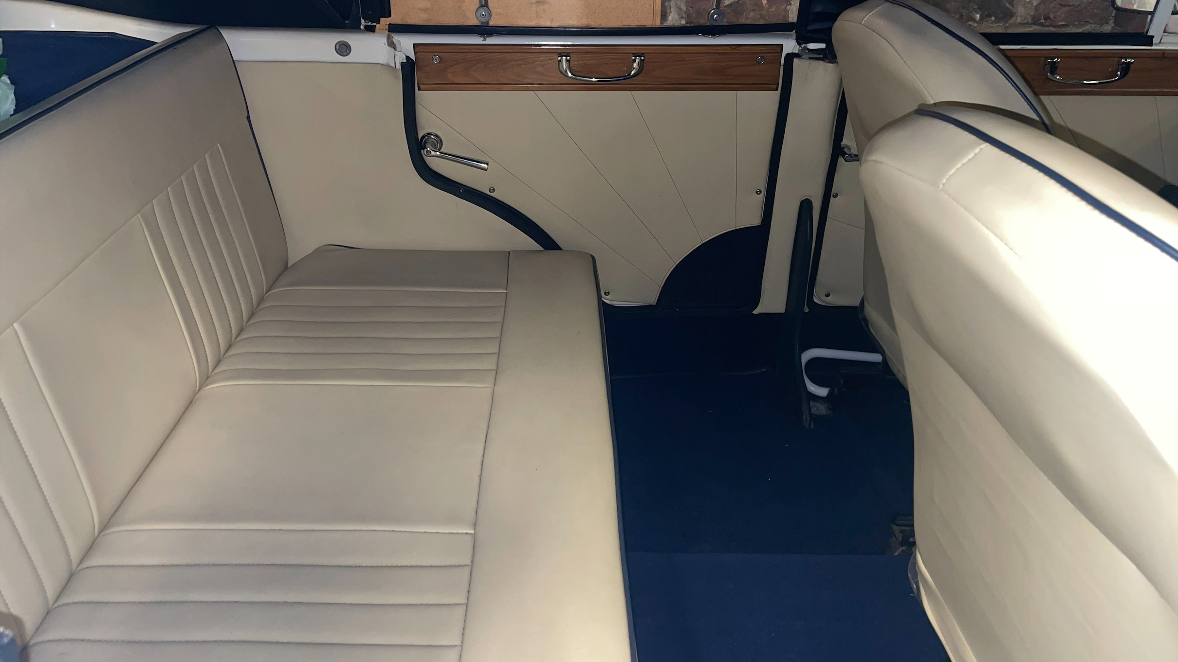 Inside rear of a Beauford with cream leather seat and royal blue carpet showing a large legroom for rear passengers.