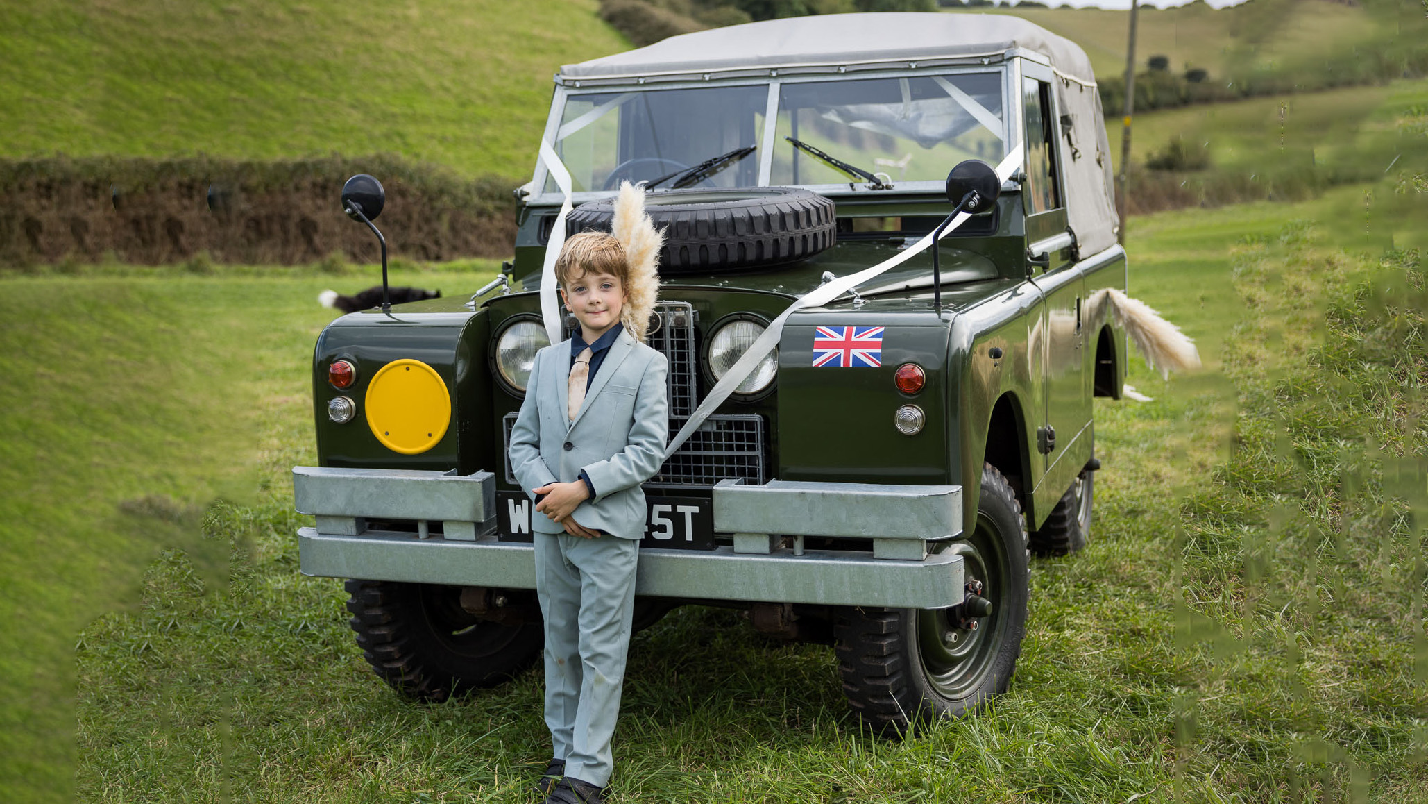 Page boy standing in front of a classic Land Rover